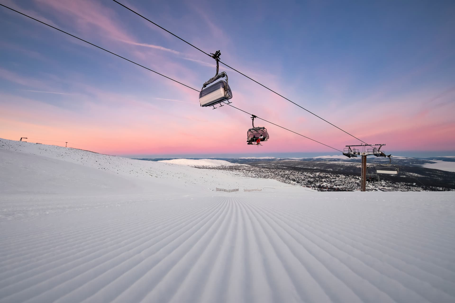 Skiiers being transported to top of mountain on chairlift at sunrise